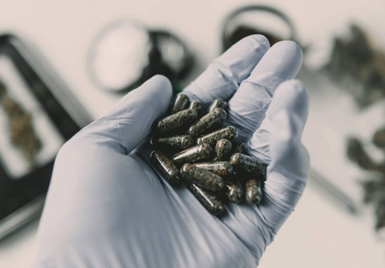 Pharmaceutical gloved hand holding cannabis extract capsules for medical cannabis treatment in the UK